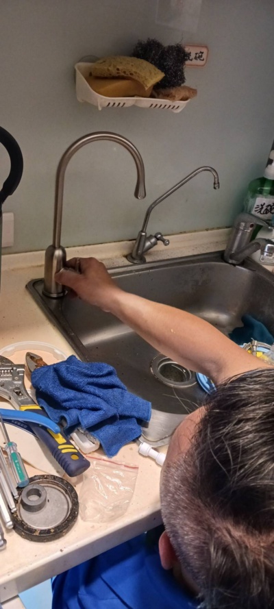 圖二，師傅正在測試安裝完成的新淨水器是否正常運作。