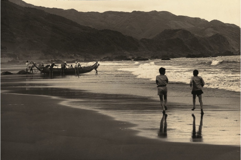 圖7：兩個小朋友奔跑向海岸邊一艘牽罟的漁船。