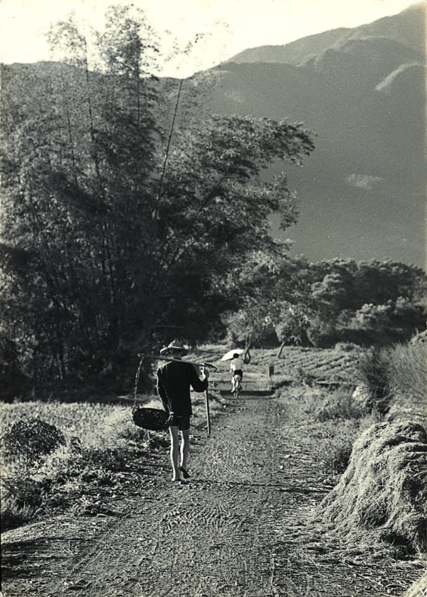 圖2：早晨一位戴著斗笠著扁擔竹籃的勞動者，赤腳步行遠離。