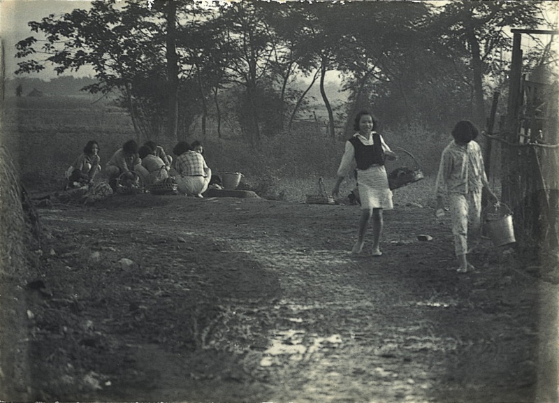 圖11：八位婦女帶著衣服在水源地洗衣，其中兩位洗完提著衣服，面露笑容的步行返家。