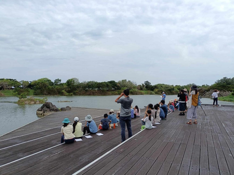 圖7：學員們以望遠鏡觀察在石塊上休息的花嘴鴨。（嚴麗 攝）