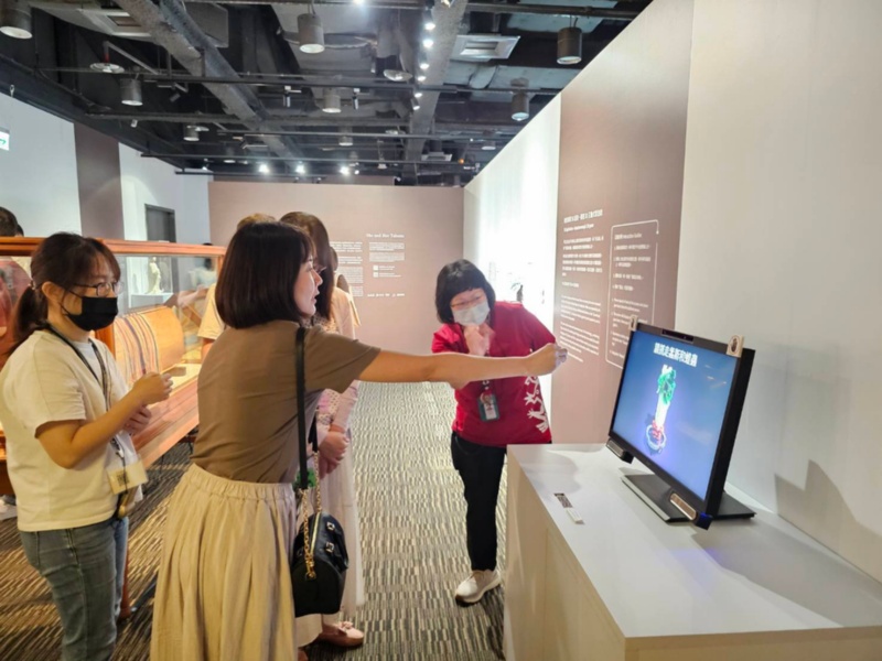 圖4：人事處同仁參觀本館故宮特展與展示螢幕進行互動。