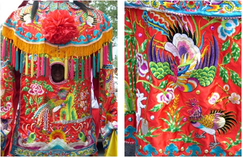 霞服以紅色、粉色系為主，以鳳凰為主體圖紋，間以牡丹花陪襯。