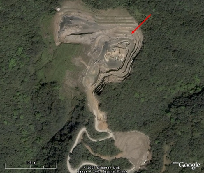 圖2員山礦區衛星圖。圖中箭頭為主礦區位置（下方較小區域可能為次礦區），面積約4公頃，礦區周圍很清楚可看到三條主要工作台階，是開挖和運送礦體機具通行的道路。（圖片取自google earth網站）