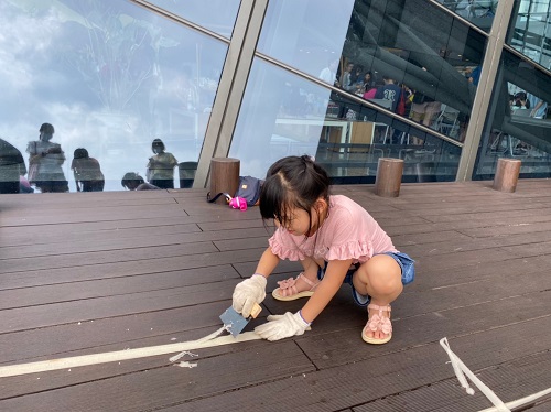 參加活動的小朋友蹲在地上奮力地刮香蕉絲