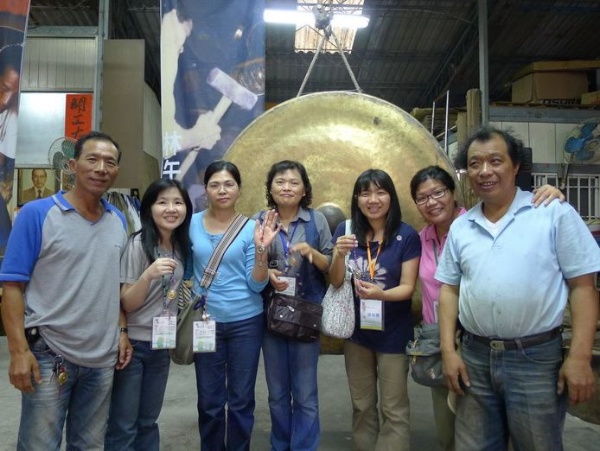 遊客完成DIY小銅鑼後在特製的大銅鑼前合影，右一為林午銅鑼第二代傳人林烈旗