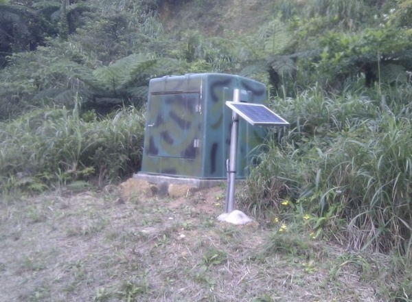 圖10 龜山島的微震站。微震記錄器放置在圖中的綠色儀器屋中，外面直立的平面板為太陽能板。