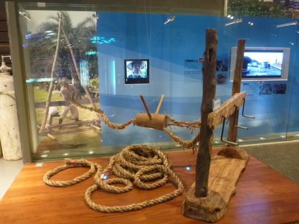在本館2樓展出的月桃繩及製繩工具，月桃繩製繩工具的製作原理與草繩製作工具是一樣的，不同的是宜蘭漁村的月桃繩較粗、長度長，因此整組機具比稻草繩機具更大，所須的人力也更多