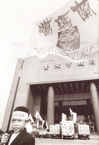 孩子舉著旗站在台北市政府的廣場，希望有人大聲叫出：「噶瑪蘭族」。