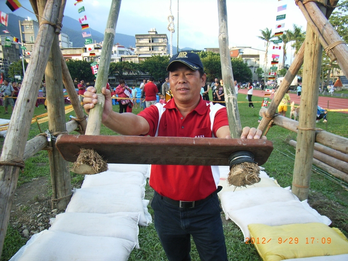 圖4：鞦韆達人陳再田展示韆板與其底部承載的桂竹根結。置於地上兩側者，即為安全防護之粗糠包。（101.9.29）