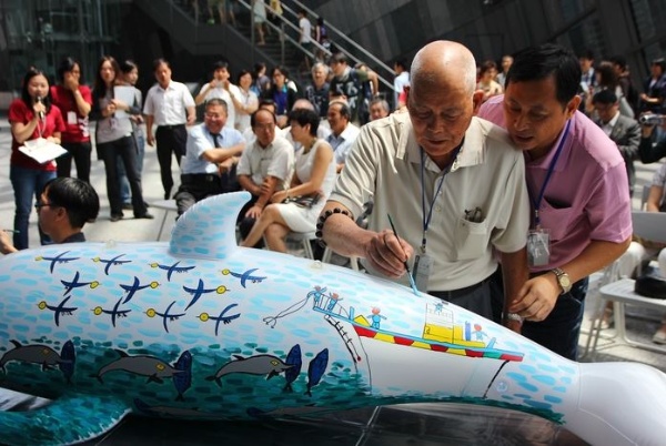 劉生根先生(左，右邊為劉先生的兒子)以舊時海豚搶食漁獲為題彩繪