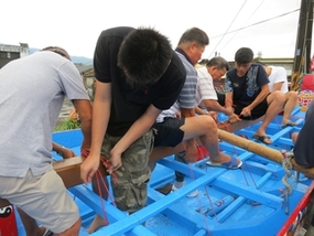 圖3：勒肚—洲仔尾長者教導年輕者，將船底間隔横木（肋骨）用電線勒住，繫於「龍骨」。（102.6.12. 葉佳勛 攝）