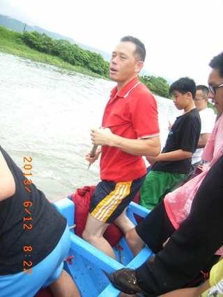 圖9：競渡達人賴湧聰於巡河獻紙中，教導青、少年，示範扒划動作，膝蓋頂住粗糠包。（102.6.12. 郭世良 攝）