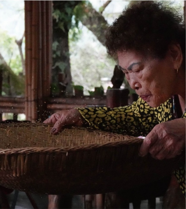 將集中在圓篩上的小米初步過篩，一邊甩篩、一邊吹氣，可將外殼與其他較輕的雜質吹出圓篩。